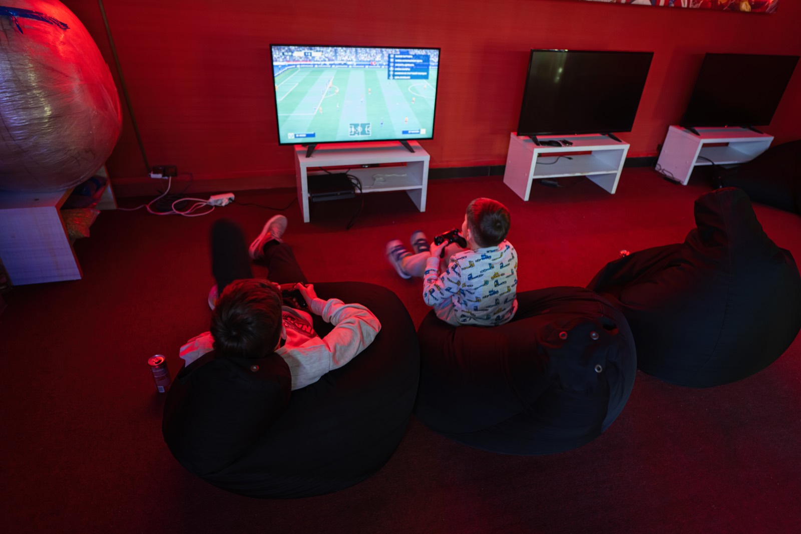 A gaming café floor with rigs along the wall and beanbags in front of them